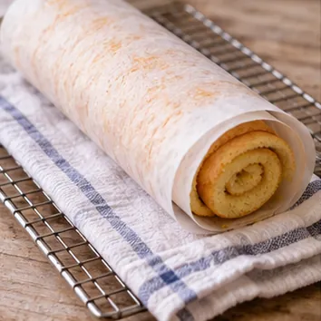 Gâteau roulé à la confiture : prérouler et laisser tiédir, biscuit préroulé avec le papier entre les couches.