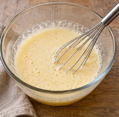 Gâteau invisible aux pommes : fouetter les œufs et le sucre — Mélange liquide légèrement mousseux.