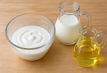 Gâteau au yaourt à la vanille : peser le yaourt et mesurer les liquides — Yaourt pesé, liquides mesurés.