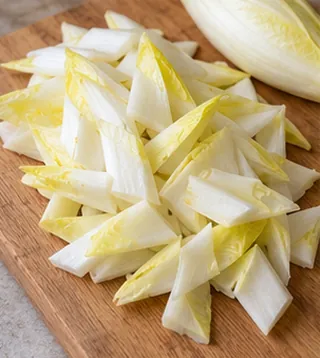 Retirer le cœur dur et couper : préparation de salade d’endives aux noix et au roquefort
