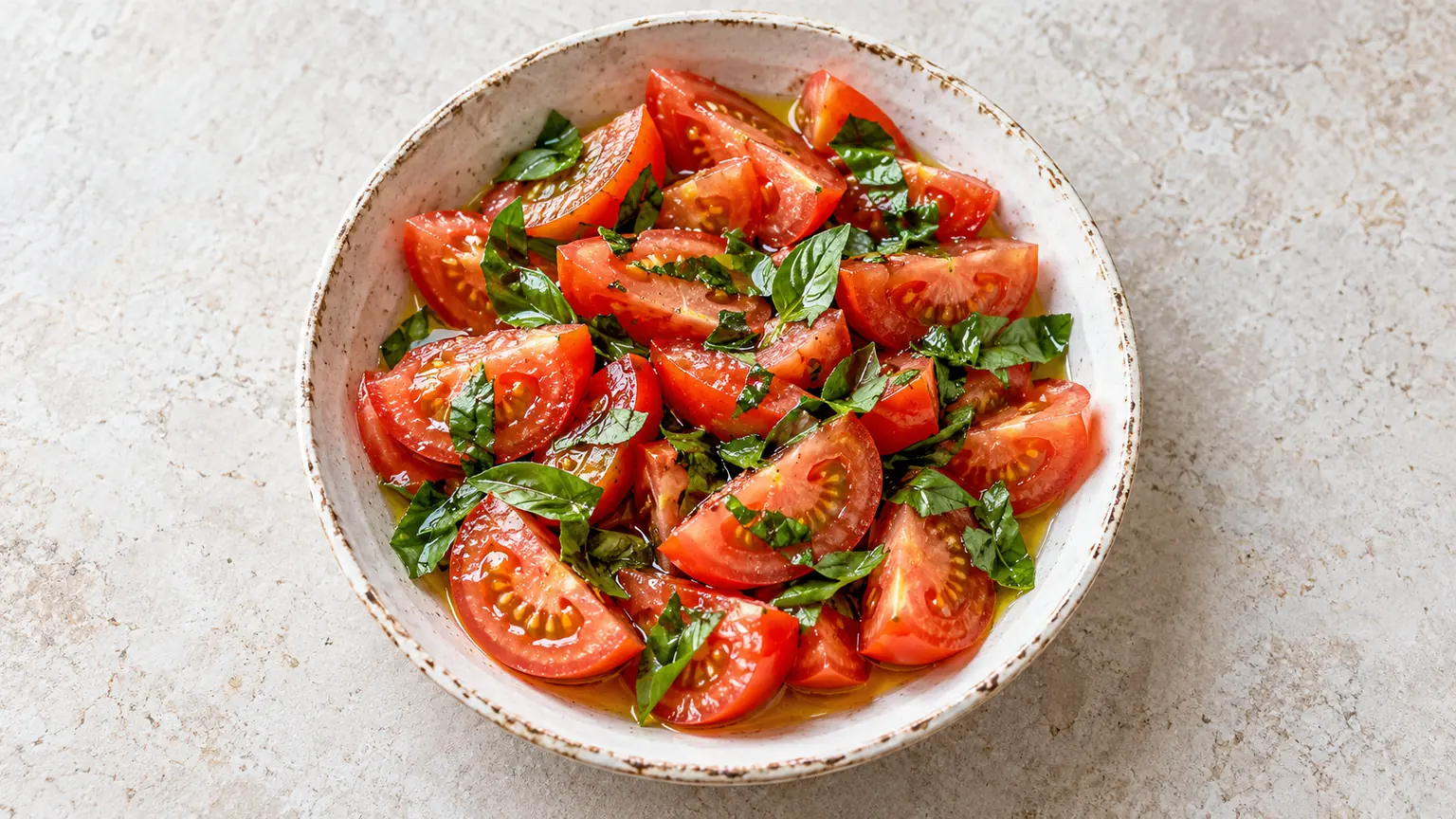 Salade de tomates au basilic maison, légumes et assaisonnement visibles dans le plat de service